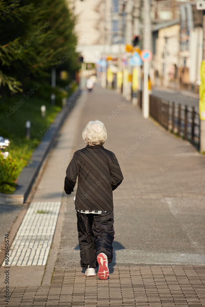 京都の町並みでジョギングしているシニア女性の後ろ姿