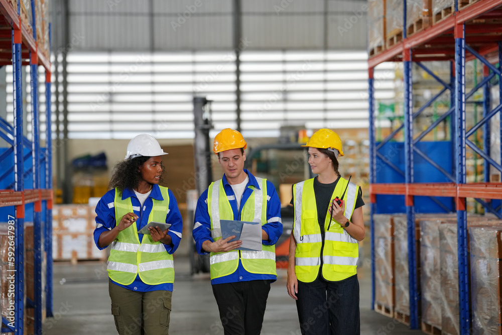 Multiethnic industrial workers checking their logistic lists while working with transportation of goods in warehouse Multiethnic industrial workers checking their logistic lists while working with transportation of goods in warehouse