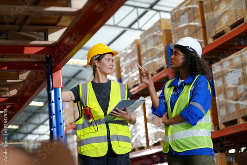 Multiethnic industrial workers checking their logistic lists while working with transportation of goods in warehouse