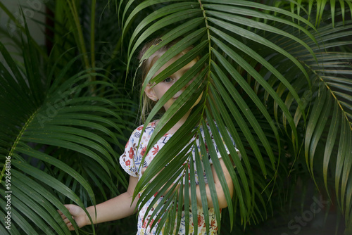 Candid outdoor portrait of adorable 5 years old girl between palm leaves  tropical vacation concept