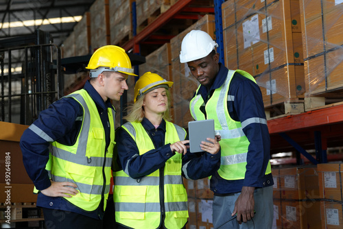 Multiethnic industrial workers checking their logistic lists while working with transportation of goods in warehouse