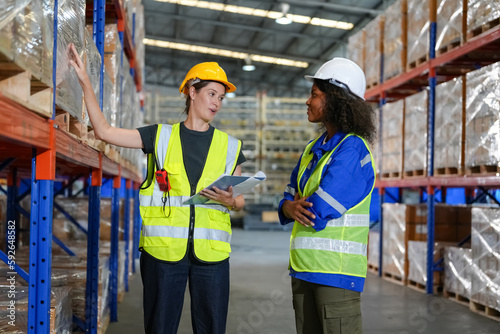 Multiethnic industrial workers checking their logistic lists while working with transportation of goods in warehouse © FotoArtist