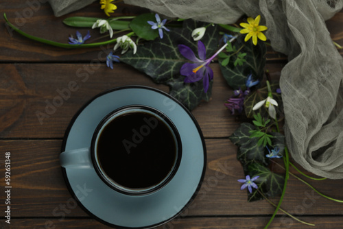 brown wooden background with spring flowers, leaves and coffee