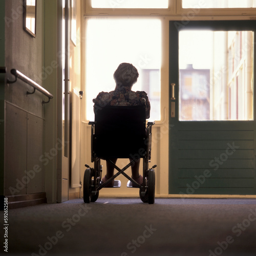 Fotografia, Obraz Back view of a female senior in a wheelchair in a nursing home looking outside