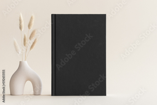 Black book mockup with a lagurus decoration on the soft yellow background.
