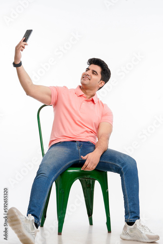 Young indian man taking selfie in smartphone.