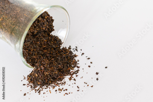 Ceylon black tea. Scattered black tea on a white background. Black tea in a glass. Isolated. Dried herbs.