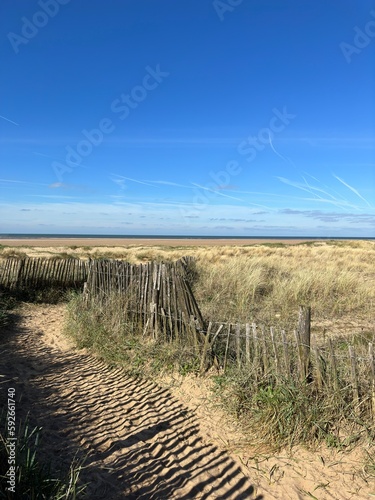Pathway between the sand dunes leading onto the beach with a blue sky background. Taken in Lytham Lancashire England. 