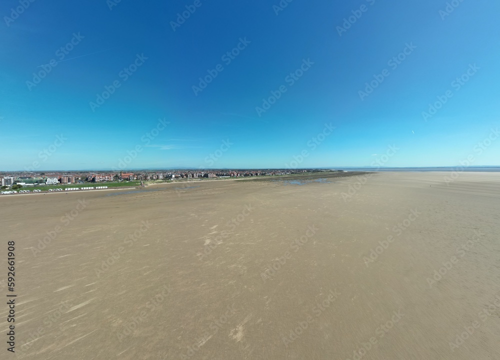 Obraz premium Aerial view of golden sand beach with low tide and blue sky background. Taken in Lytham Lancashire England. 