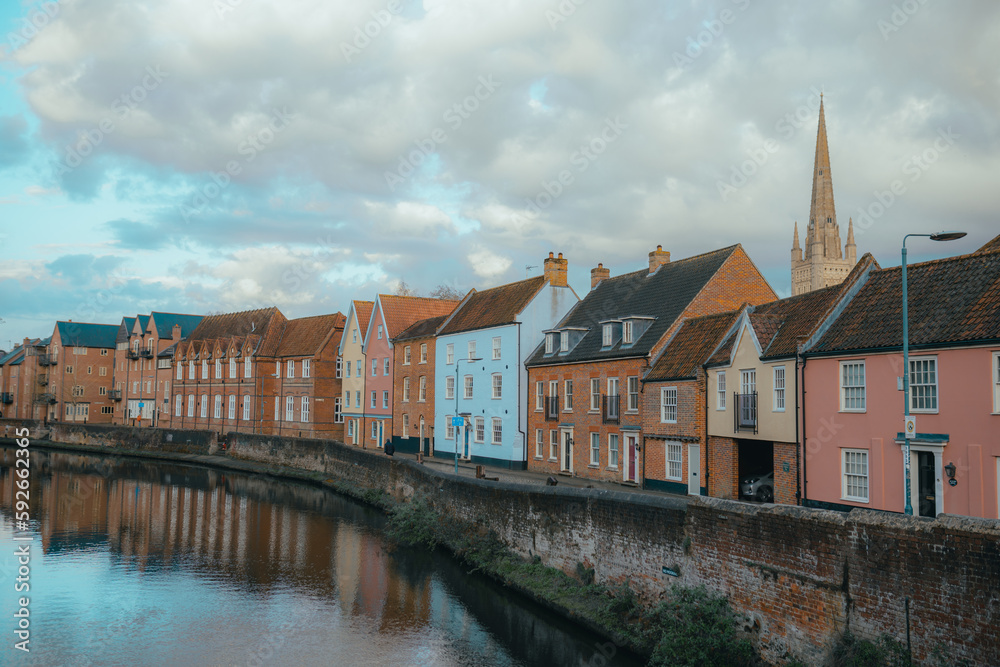 Norwich riverside houses, River Wensum in Norwich, Norfolk, United Kingdom city townhouses, colourful house blue, pink, cathedral church spire, rural location