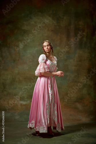 Portrait of beautiful blond girl, princess wearing fancy pink dress and standing with folded hands over vintage texture background. Elegant lady
