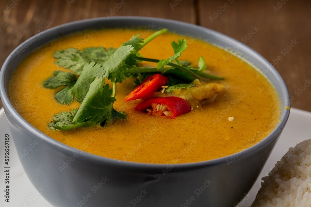 Closeup shot of orange soup decorated with greens and red pepper Closeup shot of orange soup decorated with greens and red pepper