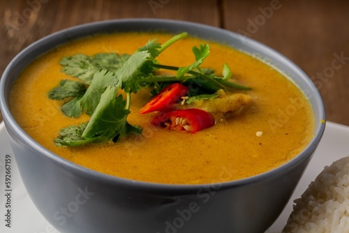 Closeup shot of orange soup decorated with greens and red pepper