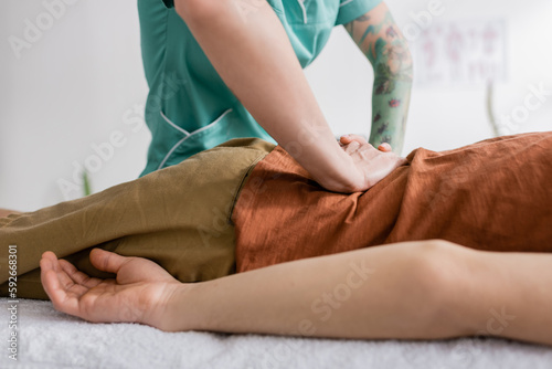 cropped view of tattooed physiotherapist doing back massage to patient in rehabilitation center.