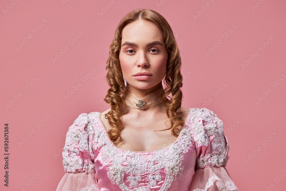 Shot of beautiful princess wearing baroque pink dress and posing over studio background with emotionless face. Medieval evil queen Shot of beautiful princess wearing baroque pink dress and posing over studio background with emotionless face. Medieval evil queen