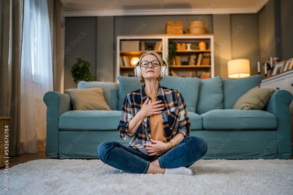 Obraz premium Mature senior woman practice guided meditation manifestation at home