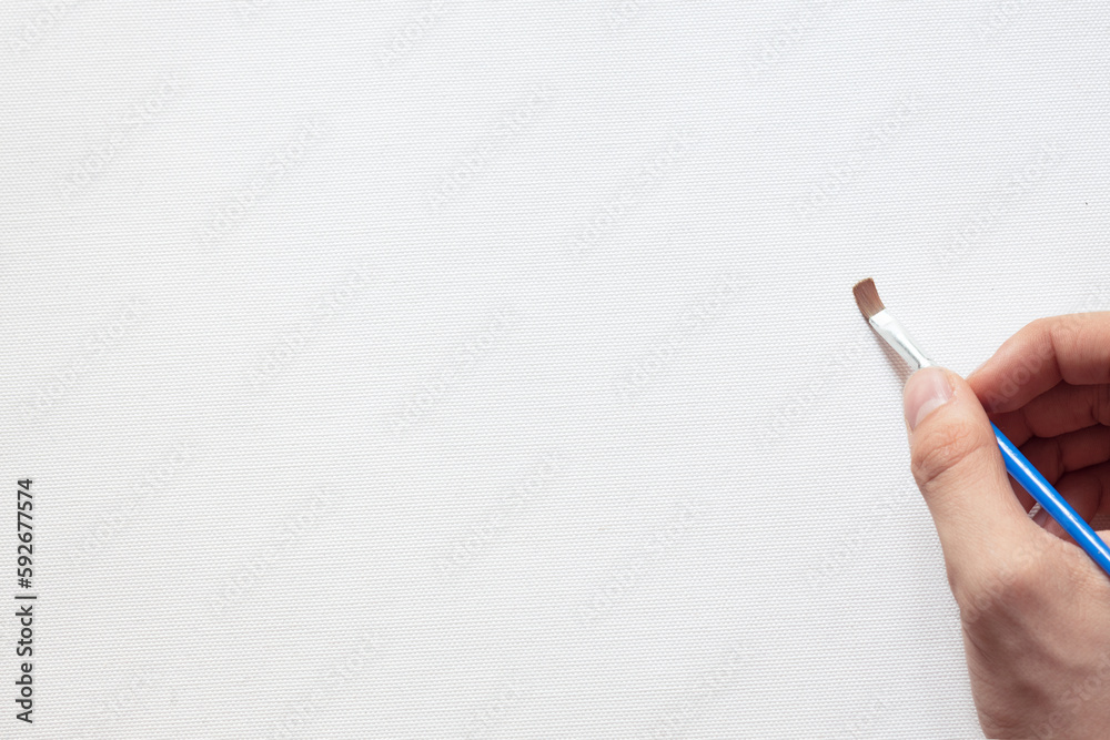 hand of the artist with a brush on the background of a white canvas, a blank sheet for creativity, free space hand of the artist with a brush on the background of a white canvas, a blank sheet for creativity, free space