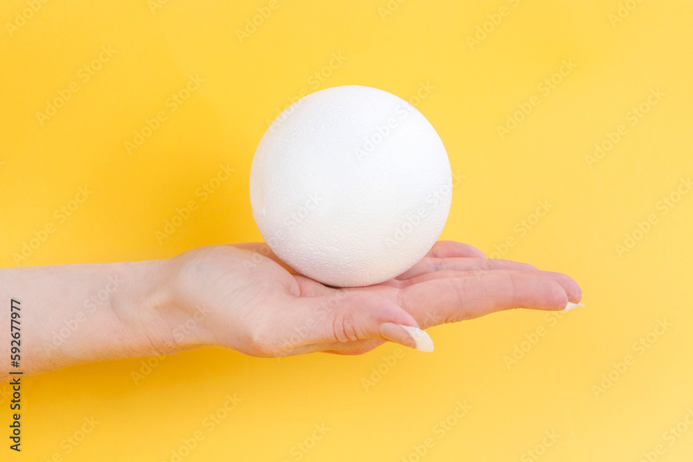 Young woman is holding a styrofoam ball in her hand. Young woman is holding a styrofoam ball in her hand.