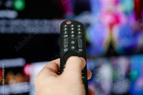 Controle de tv acionando para ligar e assistir series e filmes na televisão smart com fundo borrado.	