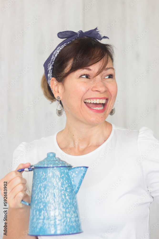 A beautiful woman smiling holds a coffee pot of delicious coffee prepared with happiness in a kitchen of a restaurant A beautiful woman smiling holds a coffee pot of delicious coffee prepared with happiness in a kitchen of a restaurant