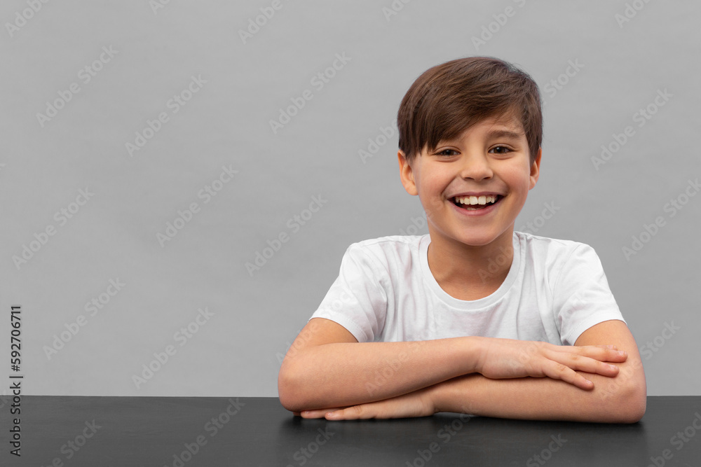 Happy schoolboys sitting at desk, classroom. Grey background Happy schoolboys sitting at desk, classroom. Grey background