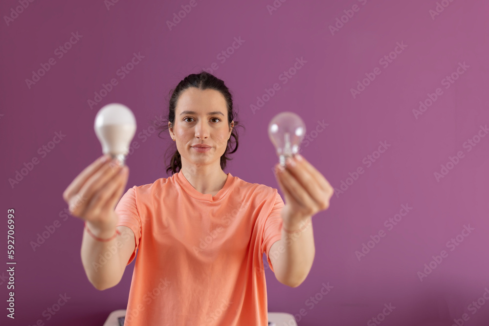 Comparison economic and normal light bulb..Eco living and sustainability concept - smiling woman comparing energy saving light bulb with incandescent lamp Comparison economic and normal light bulb..Eco living and sustainability concept - smiling woman comparing energy saving light bulb with incandescent lamp
