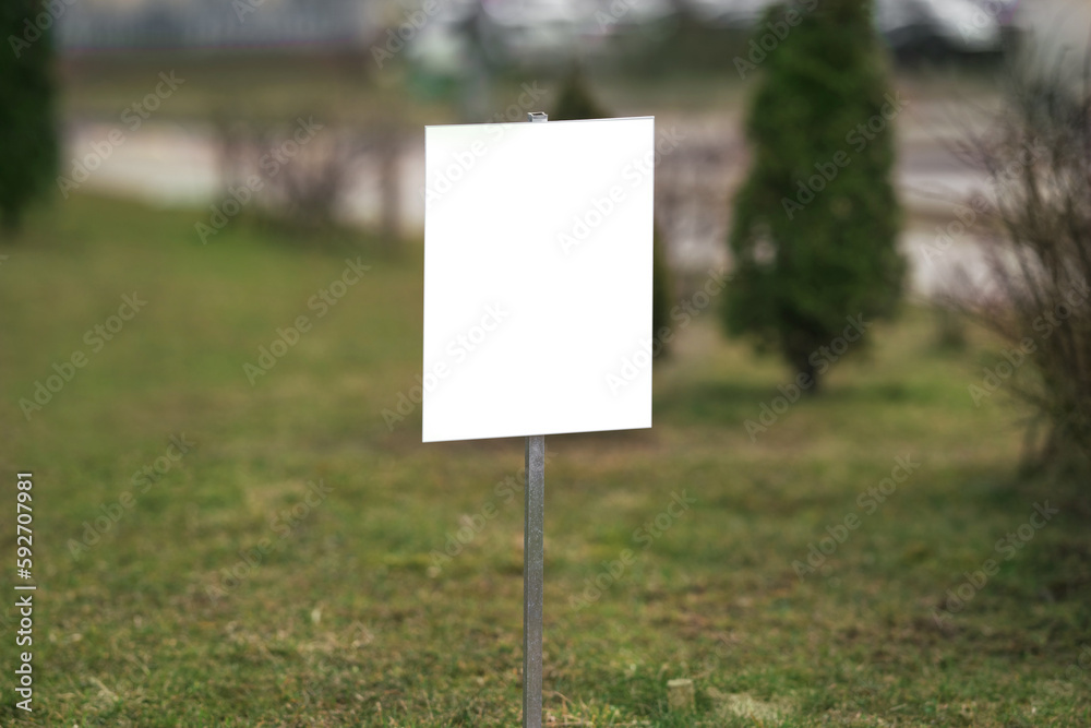 White empty information sign board with mockup space located on lawn with green grass outdoor