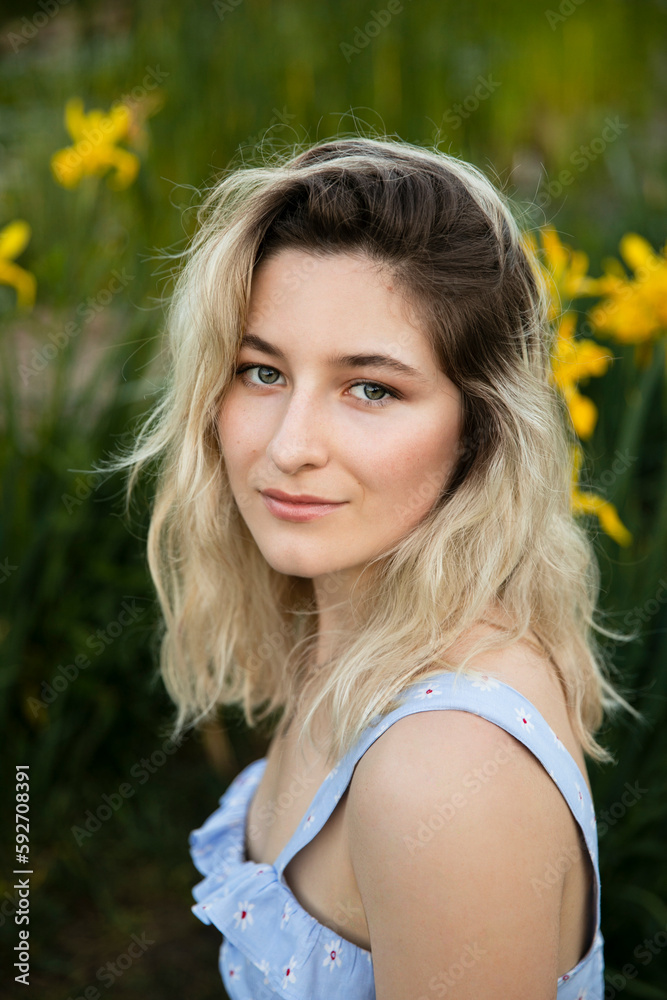 Closeup of a charming girl with blonde hair, looking at camera, yellow flowers background. Closeup of a charming girl with blonde hair, looking at camera, yellow flowers background.