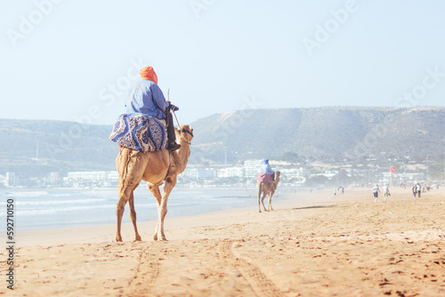 Beduin riding a camel on the main beach of Agadir, Morocco photo