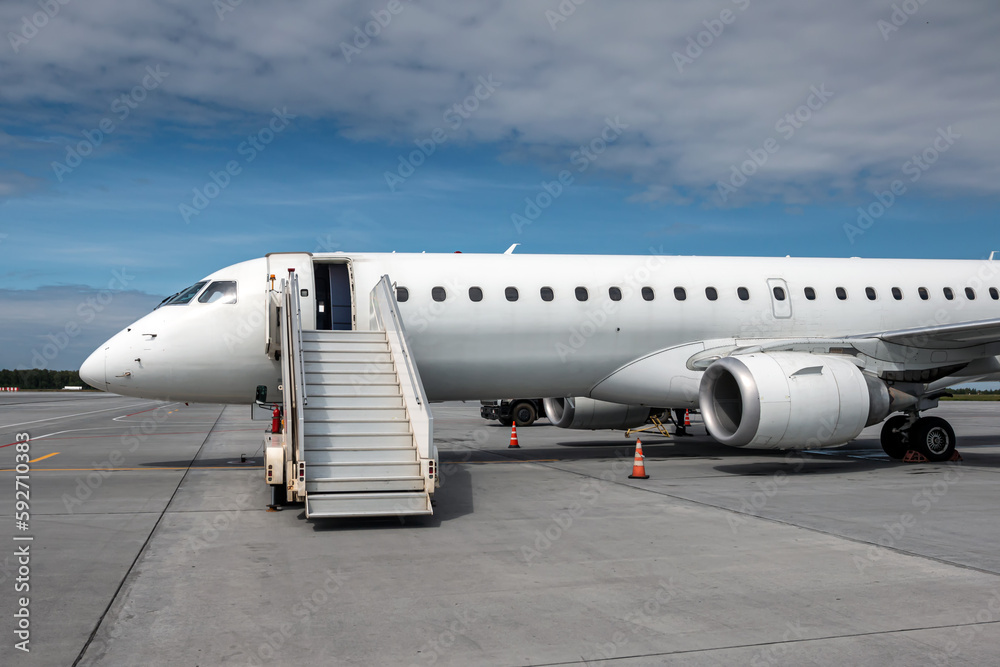 Obraz premium White passenger airliner with an aircraft steps on the airport apron