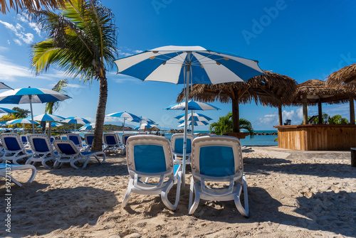 Labadee, Haiti: Beach loungers and umbrellas with tiki bar on the beach. Private resort leased by royal Caribbean Cruises. © EWY Media