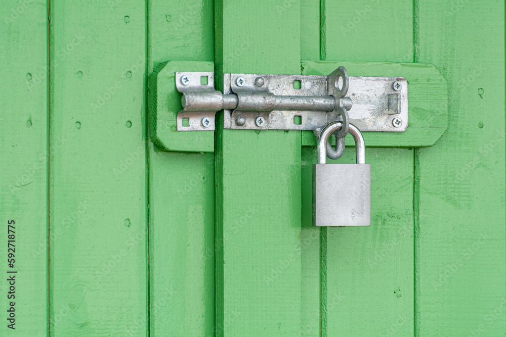 Door Locking Bolt and Padlock on a Green Wooden Door Door Locking Bolt and Padlock on a Green Wooden Door