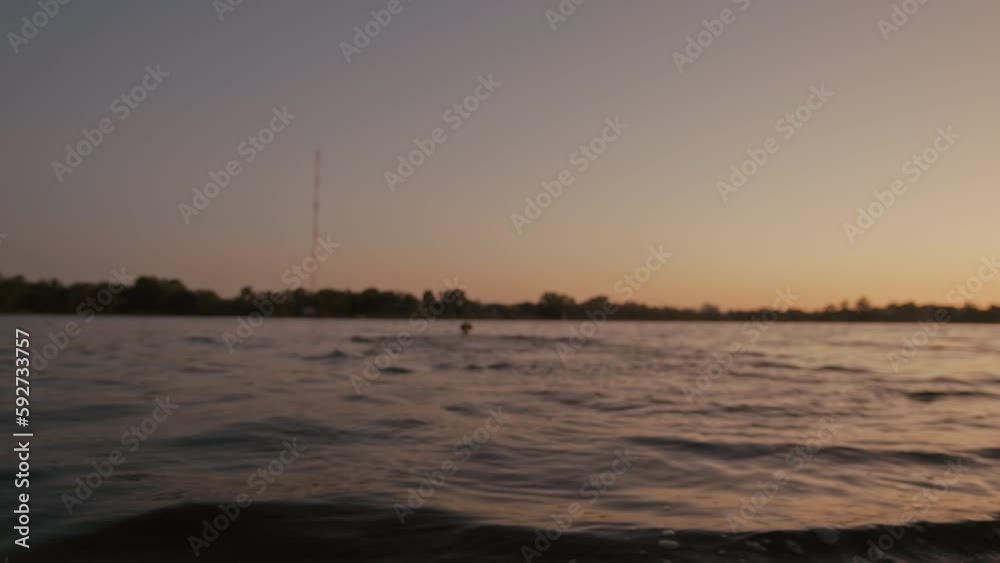 A golden retriever dog excitedly runs into a river to catch a ball thrown by its owner during a beautiful sunset evening. Selective focus, dog appears in a blur as it splashes into the water. Concept A golden retriever dog excitedly runs into a river to catch a ball thrown by its owner during a beautiful sunset evening. Selective focus, dog appears in a blur as it splashes into the water. Concept