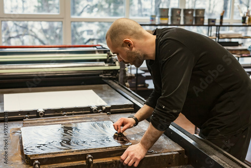 The artist is cleaning a Lithographic limestone with a clotch and chemicals in an art workshop.