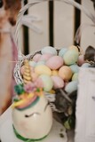 Vertical shot of a unicorn cake and colorful Easter eggs in a basket on the blurred background