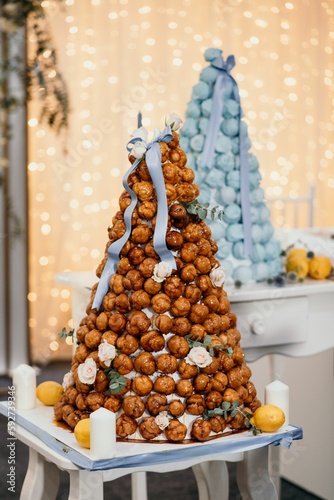 Vertical shot of a tasty croquembouche decorated with flowers on the table with candles photo