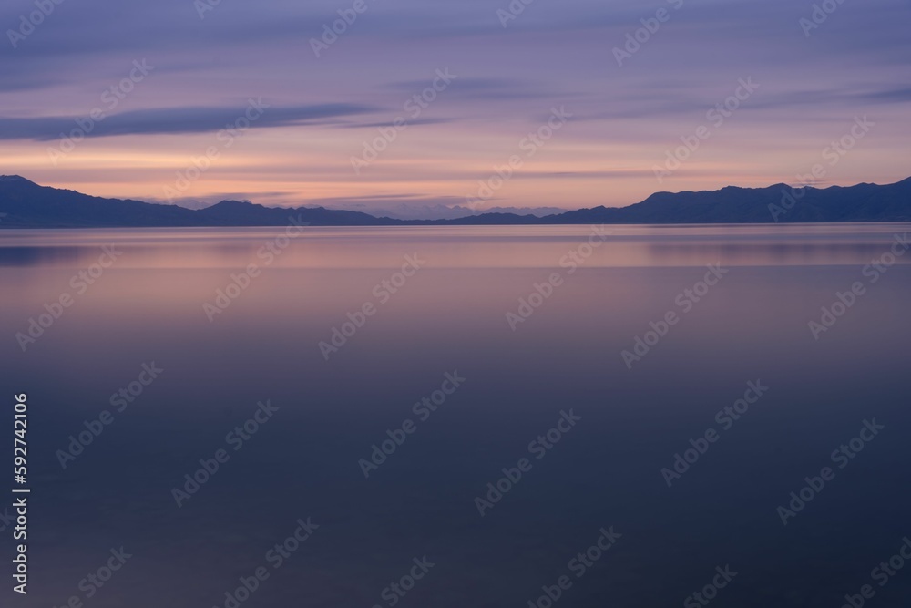 Beautiful view of a tranquil sea and hills in the background at purple sunset