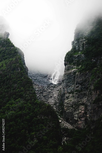 Vertical shot of cliffs in Western Brook Pond with fog