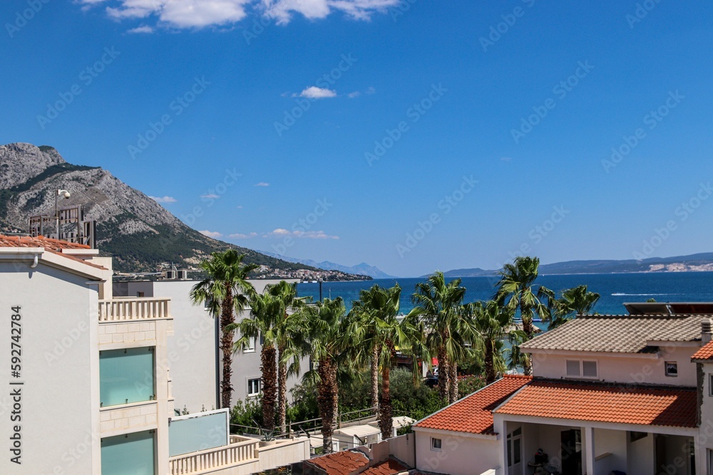 View of the ocean with buildings and mountains under a clear blue sky