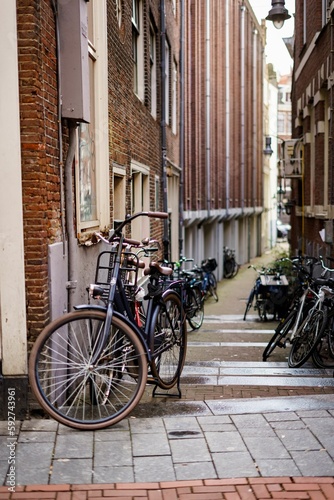 Vertical shot of bicycles leaned to walls of buildings in Amsterdam, Netherlands