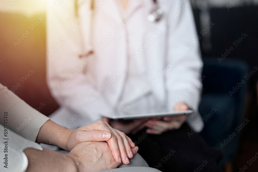 Doctor and patient sitting at sofa in clinic office. The focus is on female woman's hands, close up. Medicine concept
