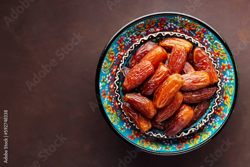 Dried dates in bowl on a dark background. Bowl of pitted dates. Food for Ramadan. Top view. Copy space
