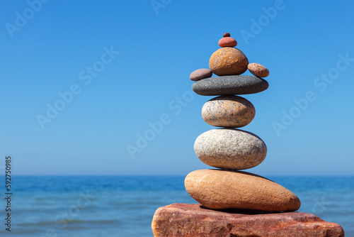 Rock zen pyramid of stones of different shapes on a background of blue sky and sea.