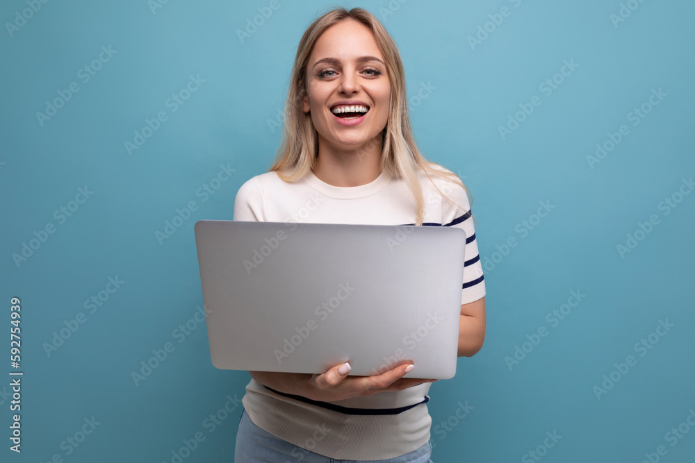 smiling funny young woman student with a laptop in her hands on a blue isolated background with copy space