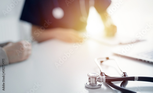Stethoscope lying on the tablet computer in front of a doctor and patient at the background. Medicine  healthcare concept