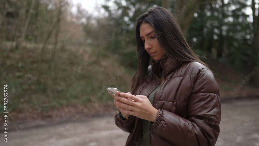 One young woman reading message on smartphone device while standing outside. Tracking shot in motion of an adult girl using modern technology One young woman reading message on smartphone device while standing outside. Tracking shot in motion of an adult girl using modern technology