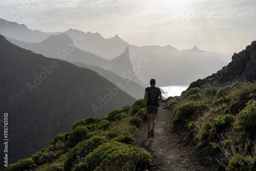 un trailer sur un chemin côtier avec des falaises, un pic et l'océan en arrière plan sous un soleil couchant