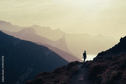la silhouette d'un homme qui domine les côtes abruptes d'un littoral sous une lumière jaune