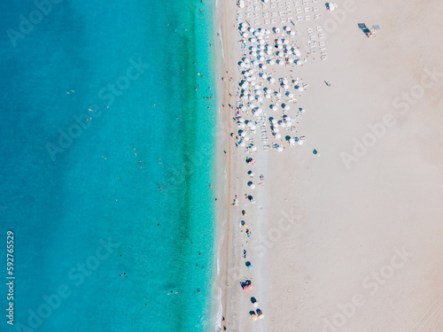 Aerial photograph capturing sunbathers enjoying the sandy Belcekiz Beach in Ölüdeniz, Muğla, Turkey, taken from a drone's bird's-eye view.
