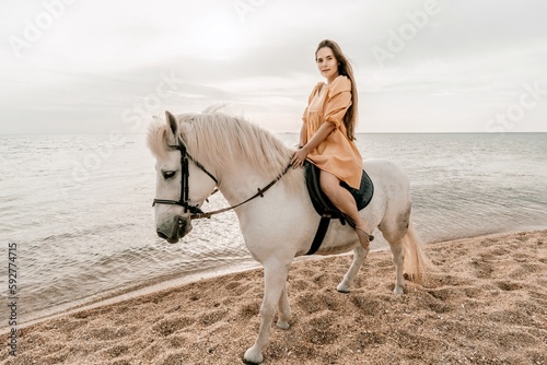Happy woman and a white horse against the background of the sky and the sea.